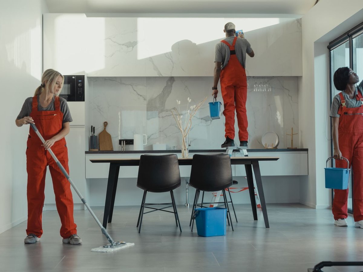Cleaning team mopping and wiping a modern kitchen and dining room